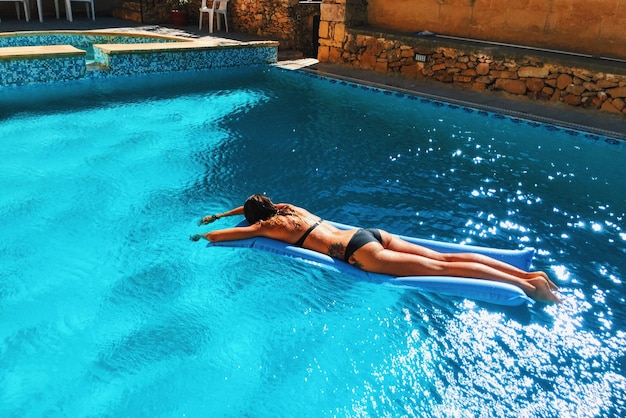 Vista de ângulo alto de mulher sensual em biquíni relaxando em balsa na piscina