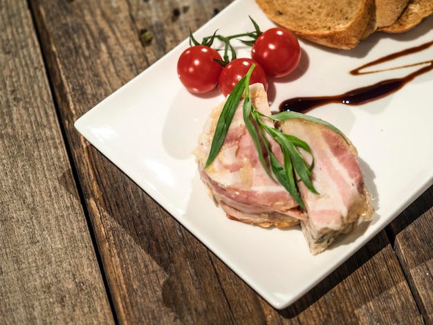 Foto vista de ângulo alto de terrine com bacon e tomates em prato em mesa de madeira