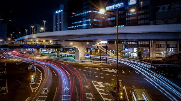 Vista de ângulo alto de trilhas de luz na estrada pela ponte na cidade à noite
