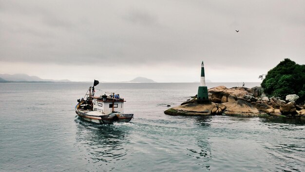 Vista de ângulo alto de um barco no mar por formações rochosas contra o céu