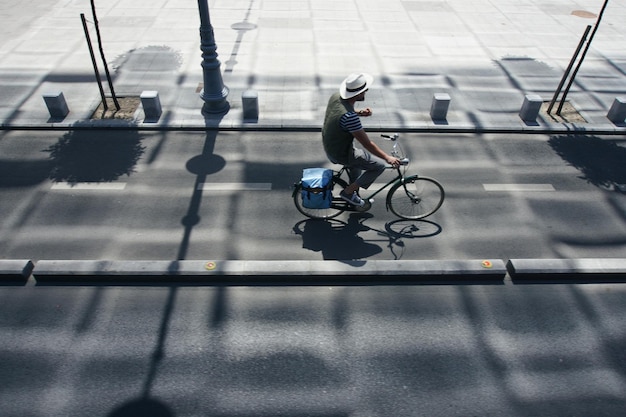 Vista de ângulo alto de um homem andando de bicicleta na estrada durante um dia ensolarado