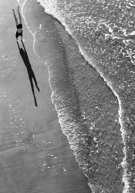 Foto vista de ângulo alto de um homem fazendo handstand na praia