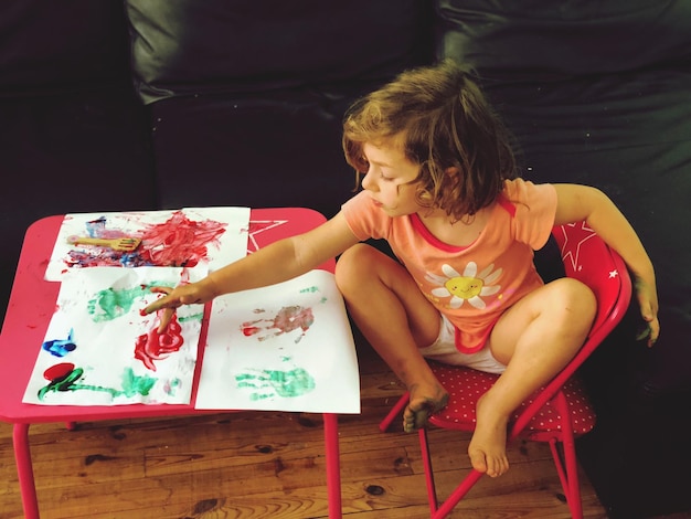 Vista de ângulo alto de uma menina bonita pintando em papel