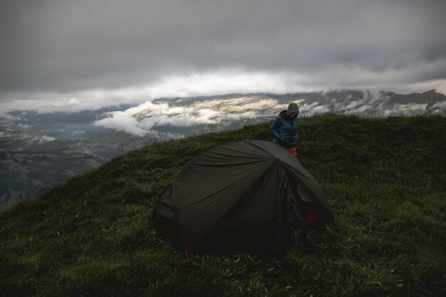 Foto vista de ângulo alto de uma mulher pela tenda de pé no pico da montanha