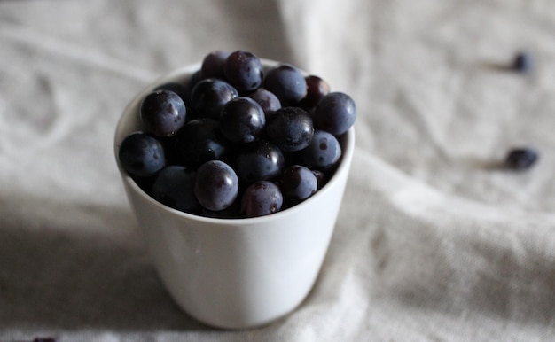 Vista de ângulo alto de uvas em recipiente branco na mesa