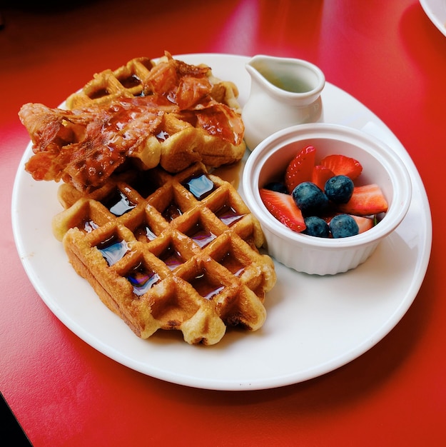 Vista de ângulo alto de waffles e bacon com frutas no prato