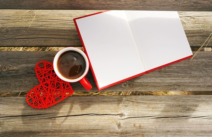 Foto vista de ângulo alto de xícara de café com forma de coração e livro aberto em banco