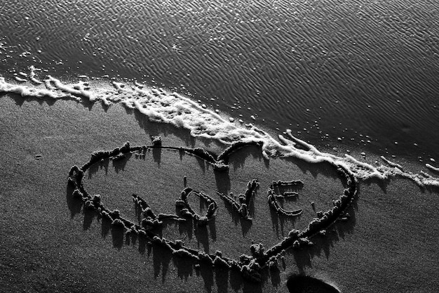 Foto vista de ângulo alto do amor com forma de coração escrito na praia de areia