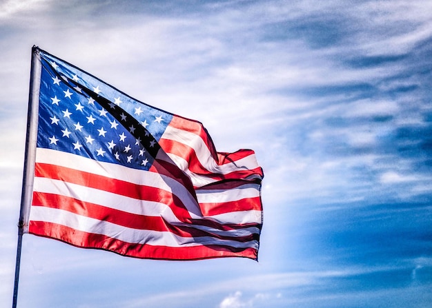 Vista de ângulo baixo da bandeira americana balançando contra o céu