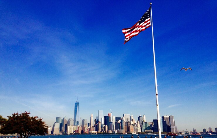 Foto vista de ângulo baixo da bandeira americana balançando contra o east river e manhattan