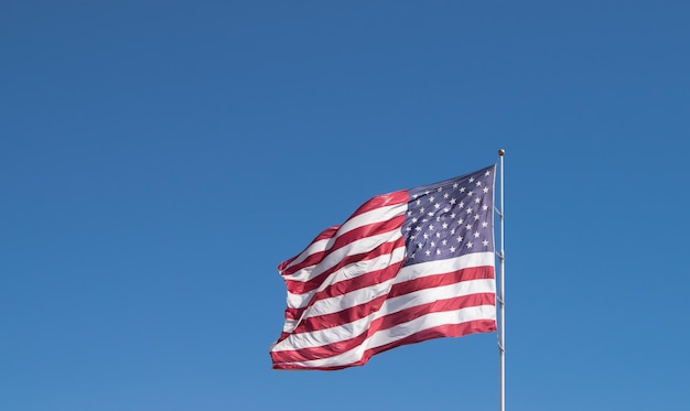 Vista de ângulo baixo da bandeira americana ondulando contra o céu azul claro