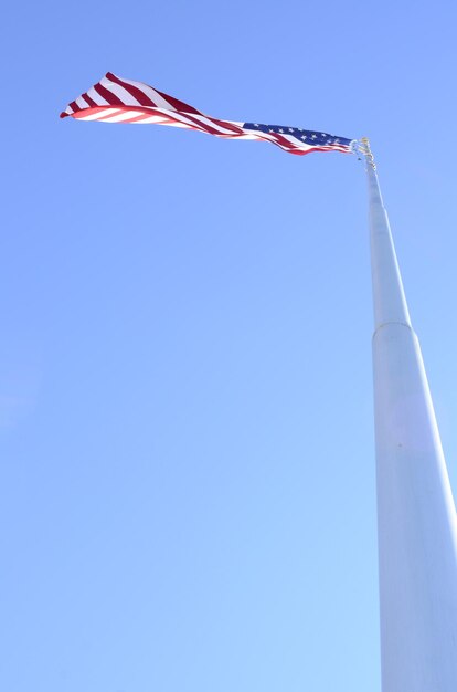 Vista de ângulo baixo da bandeira contra um céu azul claro