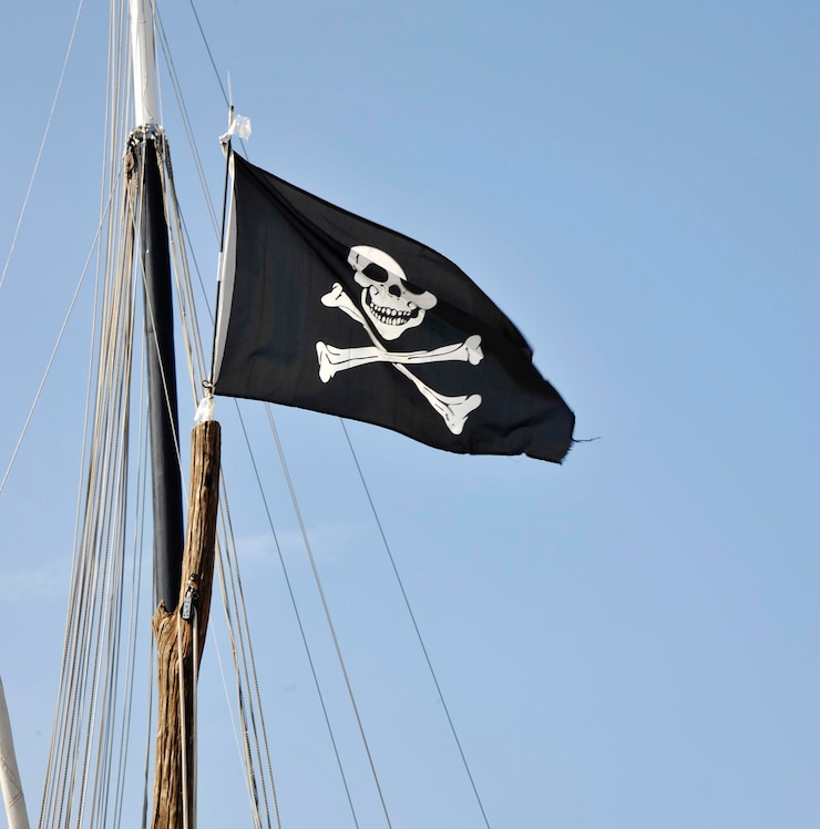 Foto vista de ângulo baixo da bandeira pirata em um veleiro contra um céu azul claro