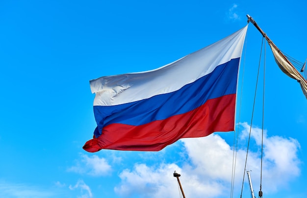 Vista de ângulo baixo da bandeira russa contra o céu azul durante um dia ensolarado