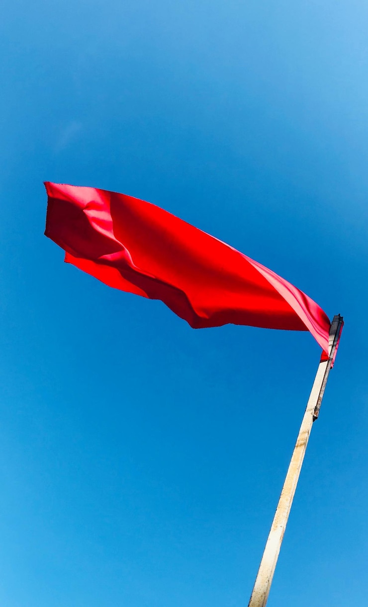 Foto vista de ângulo baixo da bandeira vermelha contra um céu azul claro