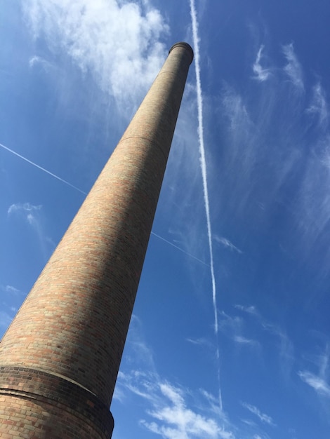 Foto vista de ângulo baixo da chaminé contra o rastro no céu azul