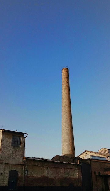 Foto vista de ângulo baixo da coluna de fumaça contra o céu azul claro