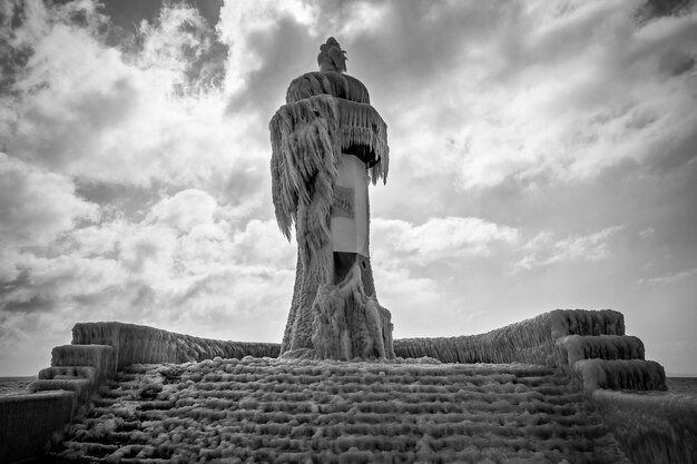 Foto vista de ângulo baixo da estátua congelada e da fonte contra o céu nublado