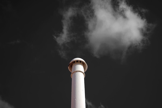 Foto vista de ângulo baixo da fumaça emitida pela chaminé contra o céu