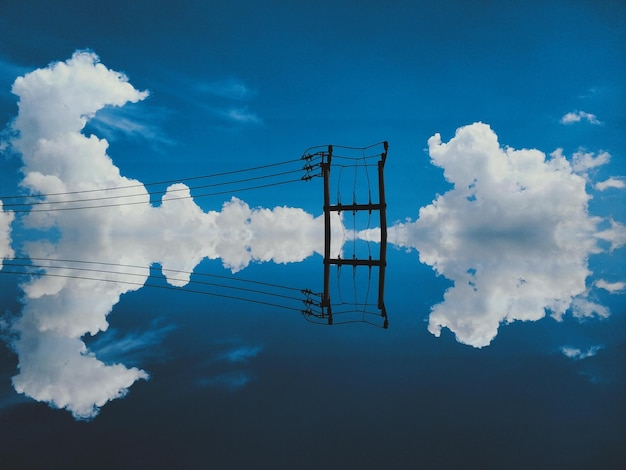 Foto vista de ângulo baixo da linha telefônica no lago com reflexo contra o céu nublado