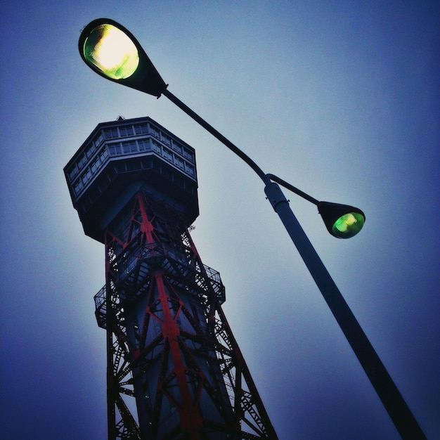 Foto vista de ângulo baixo da luz da rua iluminada pela torre do porto de hakata contra um céu azul claro