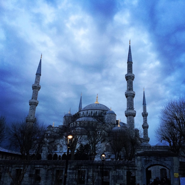 Vista de ângulo baixo da mesquita azul contra o céu nublado ao anoitecer