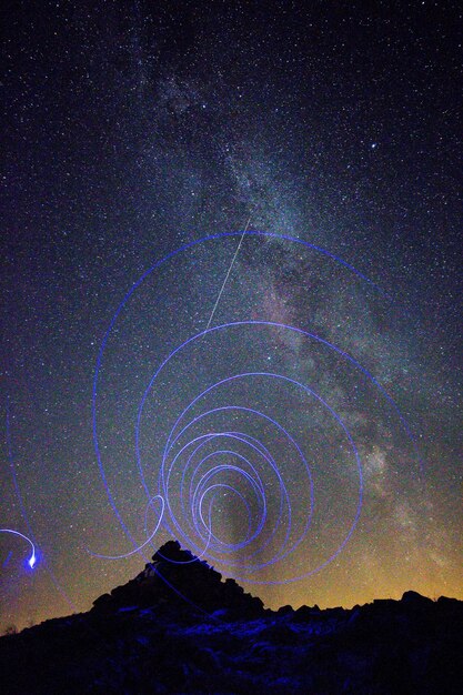 Foto vista de ângulo baixo da pintura de luz contra o campo de estrelas à noite