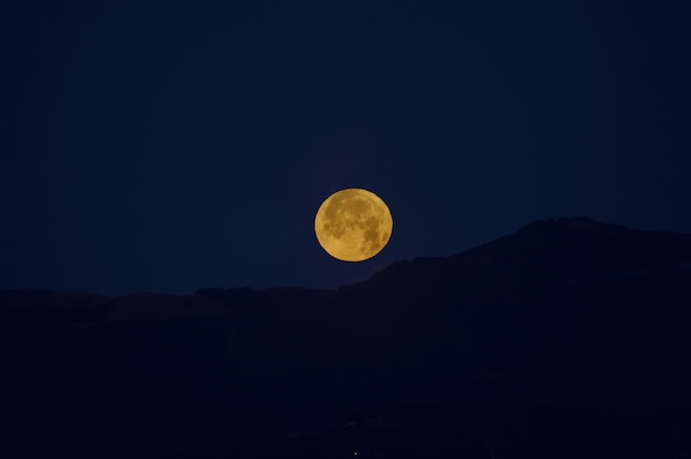 Vista de ângulo baixo da silhueta da montanha contra o céu com a lua