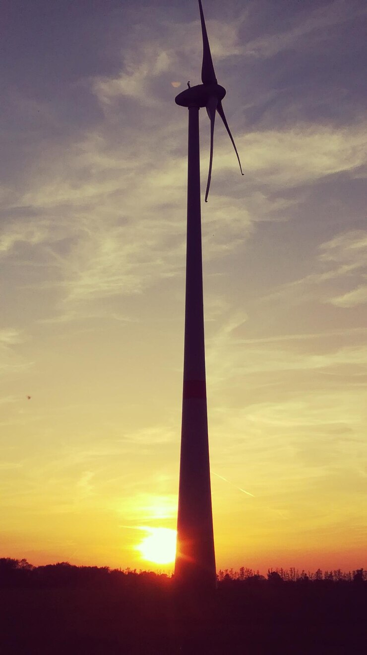 Foto vista de ângulo baixo da silhueta da turbina eólica contra o céu durante o pôr do sol