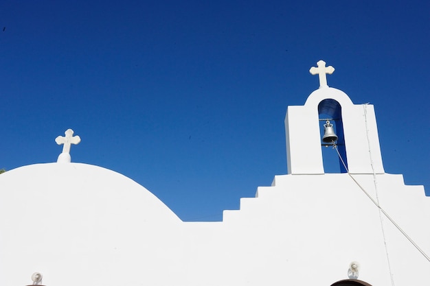 Vista de ângulo baixo da torre do sino da igreja contra o céu azul claro em Santorini