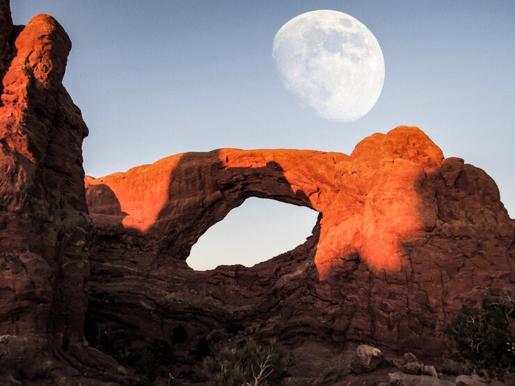 Foto vista de ângulo baixo de arco natural contra a lua