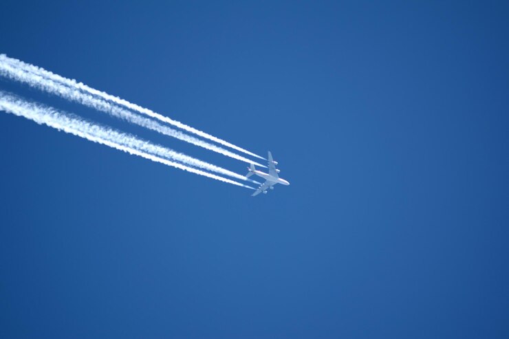 Foto vista de ângulo baixo de avião deixando rastros de vapor no céu azul