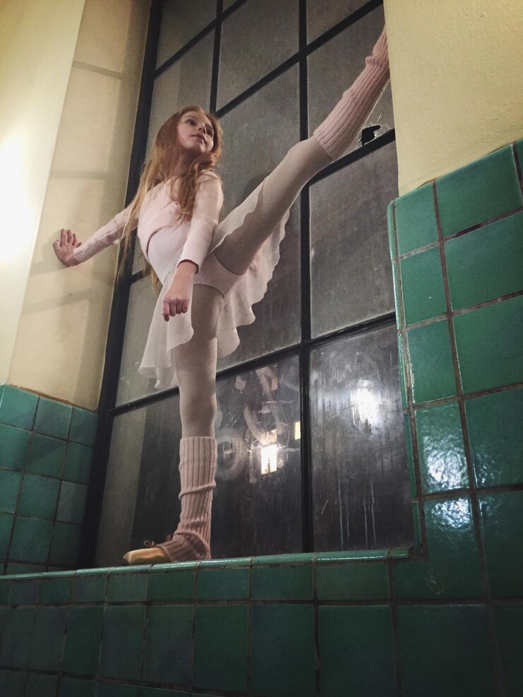 Foto vista de ângulo baixo de balerina se estendendo no peitoral da janela