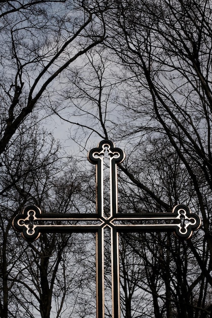 Vista de ângulo baixo de cruz religiosa contra árvores