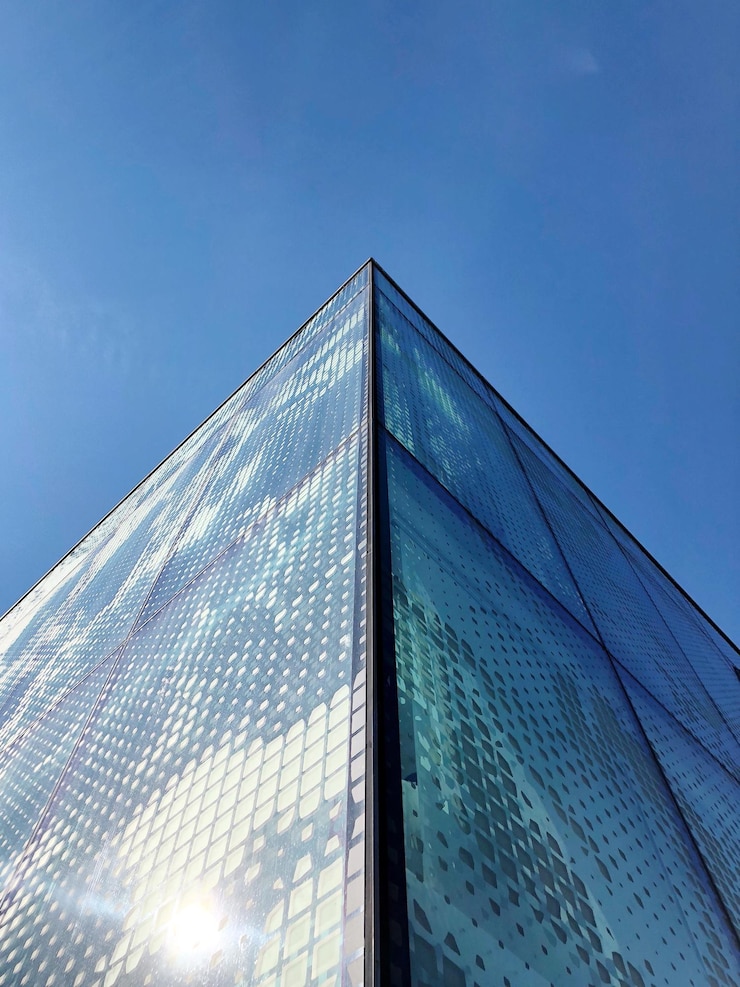 Foto vista de ângulo baixo de edifício de vidro contra o céu azul