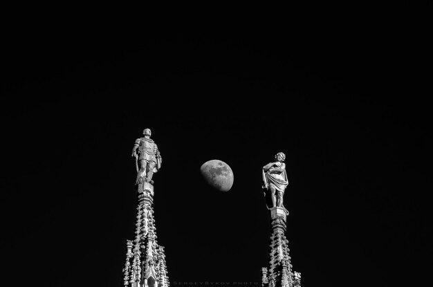 Foto vista de ângulo baixo de estátuas contra a lua