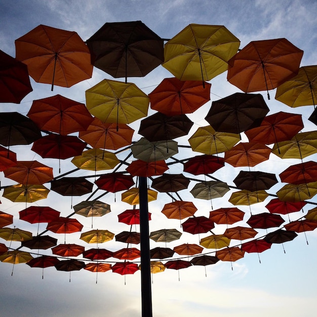 Foto vista de ângulo baixo de guarda-chuvas coloridos em poste metálico contra o céu