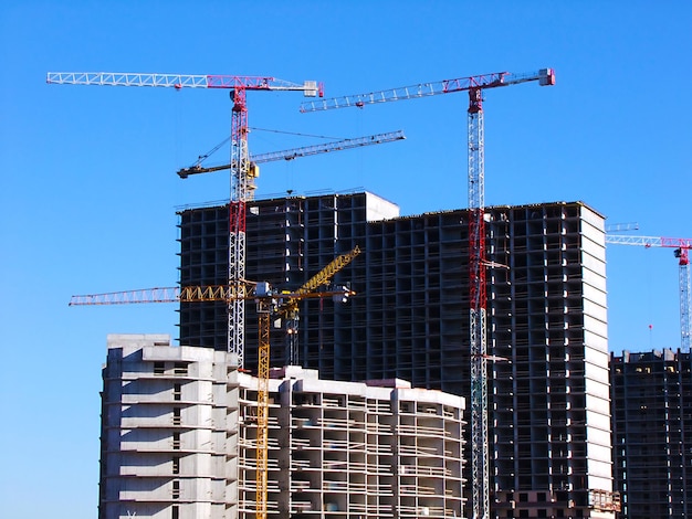 Vista de ângulo baixo de guindastes e edifícios incompletos contra um céu claro
