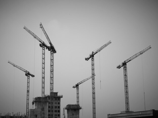 Foto vista de ângulo baixo de guindastes no canteiro de obras contra o céu