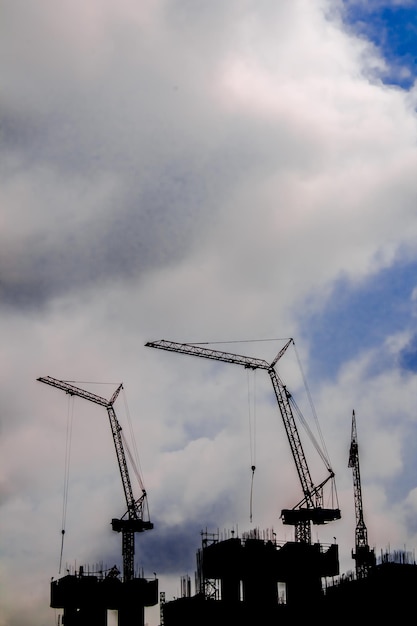 Vista de ângulo baixo de guindastes no canteiro de obras contra o céu