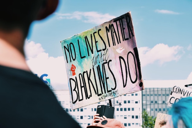 Vista de ângulo baixo de homem segurando sinal contra o céu vidas negras importa racismo demo berlin