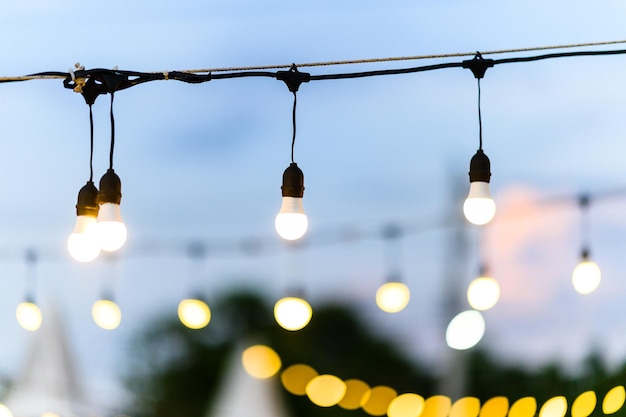 Vista de ângulo baixo de lâmpadas iluminadas penduradas contra o céu