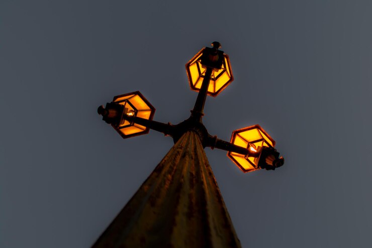 Foto vista de ângulo baixo de luz de rua iluminada contra um céu claro ao anoitecer