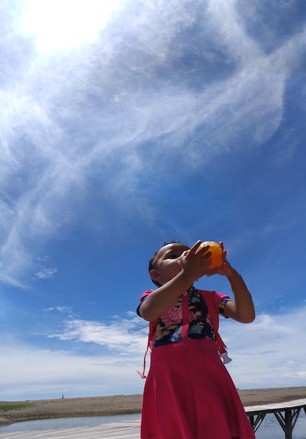 Foto vista de ângulo baixo de menina de pé contra o céu