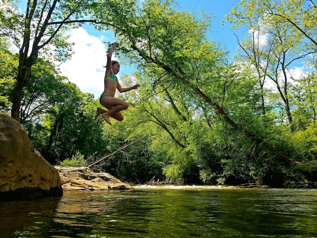 Foto vista de ângulo baixo de menina pulando no rio