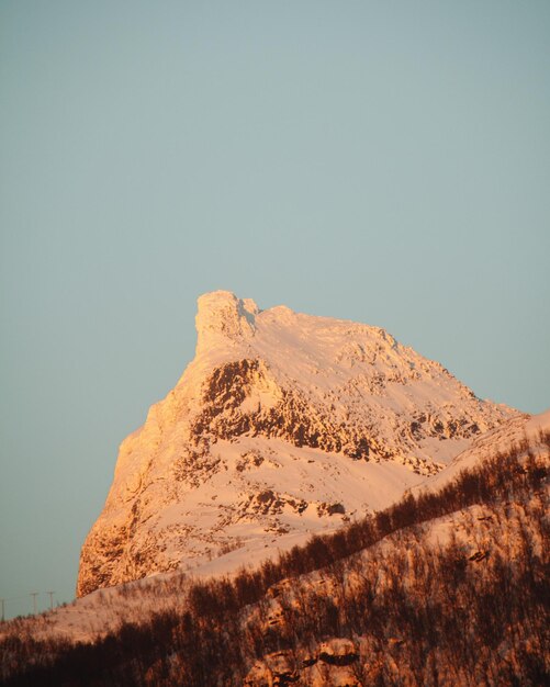 Foto vista de ângulo baixo de montanha coberta de neve contra um céu claro