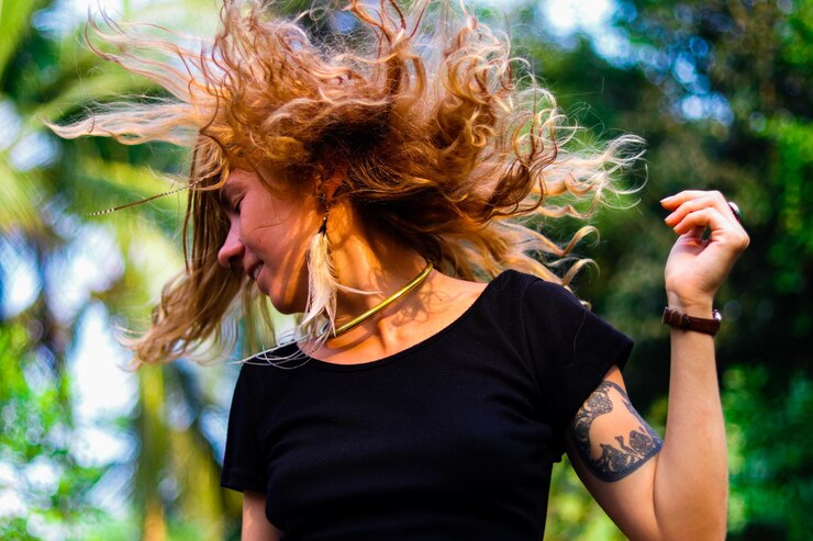 Foto vista de ângulo baixo de mulher com o cabelo desarranjado contra as árvores