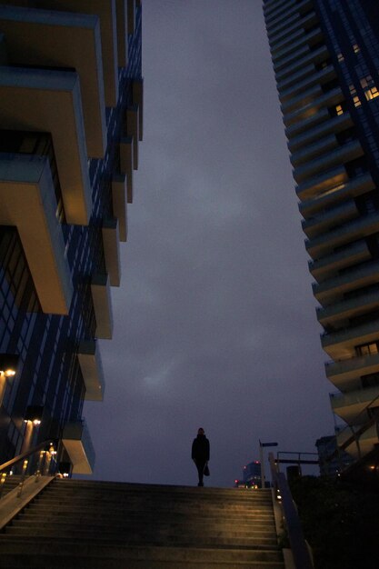 Foto vista de ângulo baixo de mulher de pé em degraus contra o céu à noite
