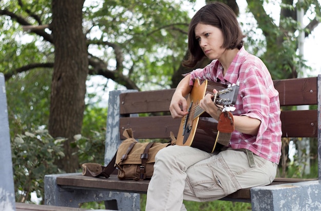 Foto vista de ângulo baixo de mulher tocando guitarra no parque