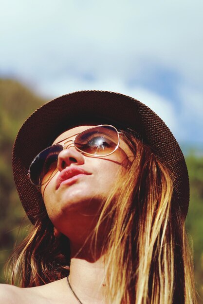 Vista de ângulo baixo de mulher usando óculos de sol e chapéu